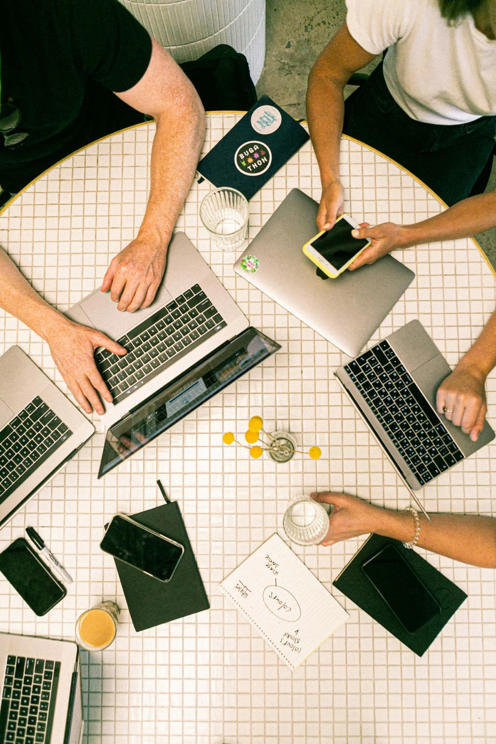 Equipe em reunião de trabalho com notebooks e cadernos, situação em que se usa um modelo de ata de reunião